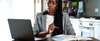 Woman sitting at table with computer and book